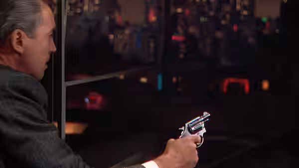 Rupert Cadell (James Stewart) holds a revolver in the dimly lit apartment