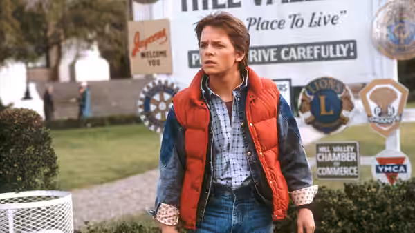 Marty McFly (Michael J. Fox) standing in front of welcome signs outdoors