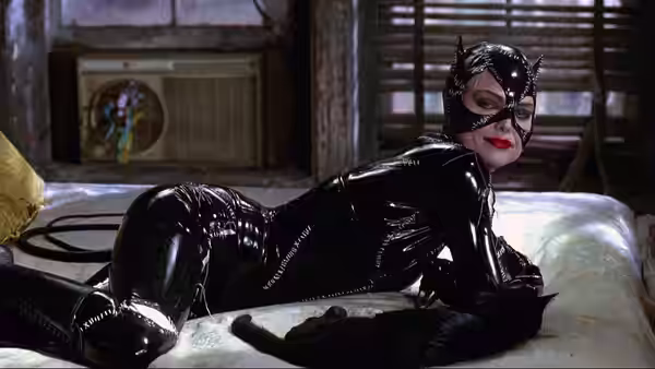 Catwoman (Michelle Pfeiffer) lying on a bed next to a black cat