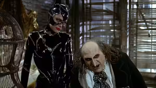 Catwoman (Michelle Pfeiffer) standing over Penguin (Danny DeVito) in an interior space