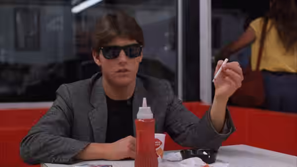 Joel Goodson (Tom Cruise) holds a cigarette at a diner table