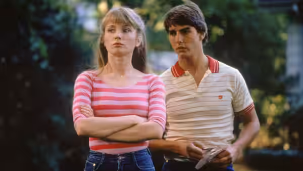 Lana (Rebecca De Mornay) stands with arms crossed beside Joel Goodson (Tom Cruise)