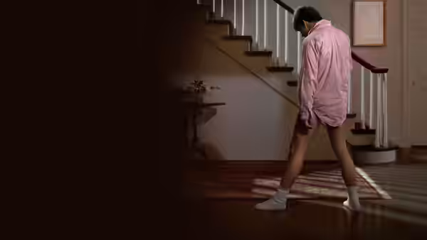 Joel Goodson (Tom Cruise) walks through a hallway in a pink shirt and socks