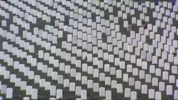 Rows of white headstones cover a large green cemetery field
