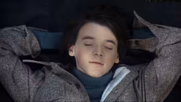 Harold (Bud Cort) lies on his back with eyes closed wearing a tweed coat