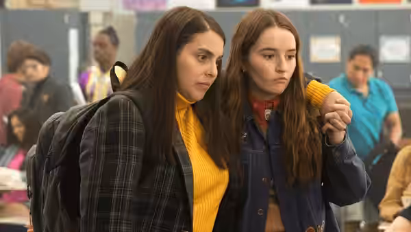 Molly (Beanie Feldstein) rests arm around Amy (Kaitlyn Dever) in busy school hallway