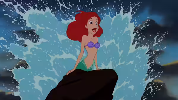 Ariel perched on a rock with a large wave splashing behind her