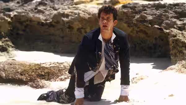 Allen Bauer (Tom Hanks) crawls across a rocky beach in a soaked suit