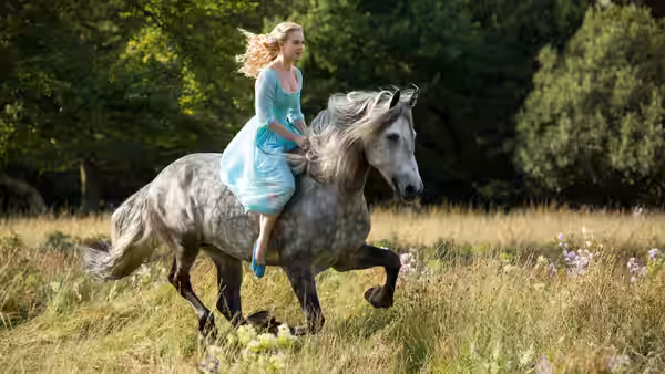 Cinderella (Lily James) rides a gray horse through a flowered meadow