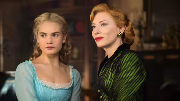 Cinderella (Lily James) stands beside Lady Tremaine (Cate Blanchett) indoors