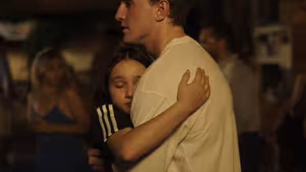 Sophie (Frankie Corio) hugs Calum (Paul Mescal) in a dimly lit room
