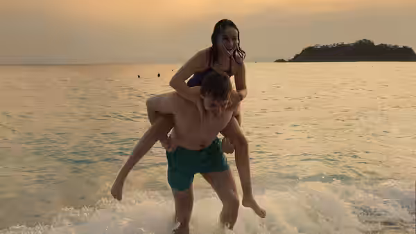 Calum (Paul Mescal) carries Sophie (Frankie Corio) on his back through shallow seaside water