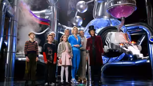 Willy Wonka (Johnny Depp) stands with children before a large industrial machine