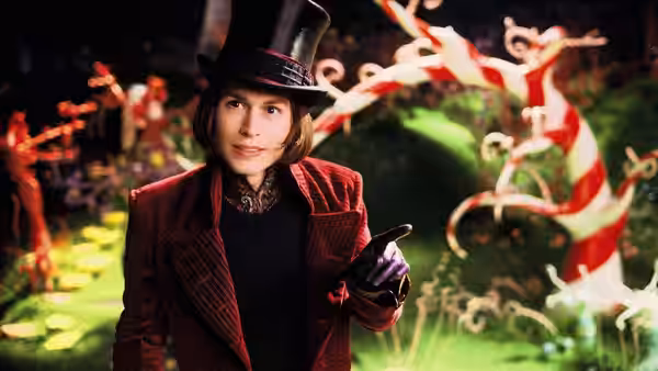Willy Wonka (Johnny Depp) points ahead in a striped red coat and top hat