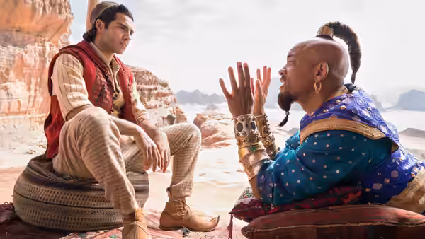 Aladdin (Mena Massoud) listening to the Genie (Will Smith) in the desert