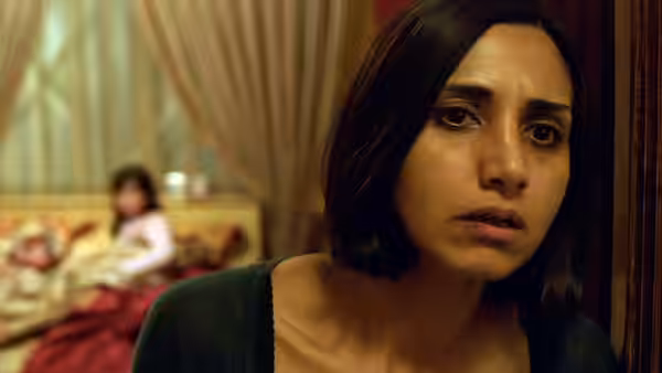 Shideh (Narges Rashidi) leans forward as a child sits on a bed behind her