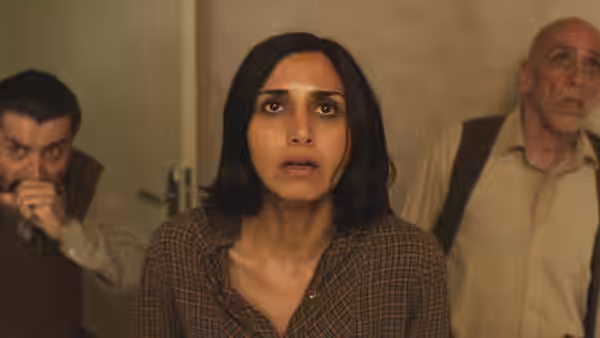 Shideh (Narges Rashidi) and two men look upward inside an apartment