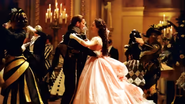 Christine and Raoul dancing together in a crowded ballroom
