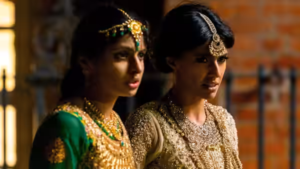 two women in gold jewelry and traditional dresses stand close together