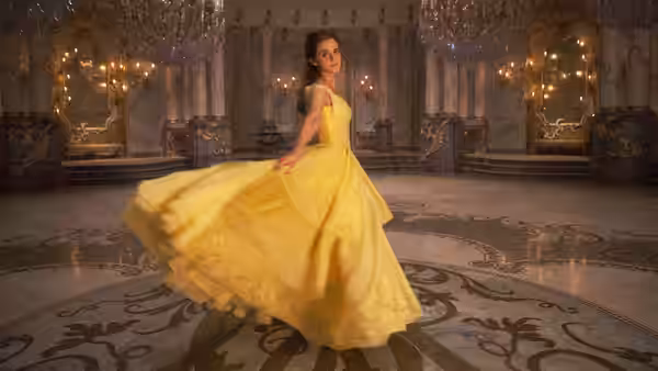 Belle (Emma Watson) spinning in a yellow gown across an ornate ballroom