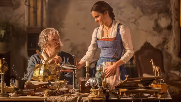 Maurice (Kevin Kline) and Belle (Emma Watson) examining mechanical devices on a workbench
