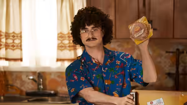 Weird Al (Daniel Radcliffe) holds up a package of bologna while standing in a kitchen