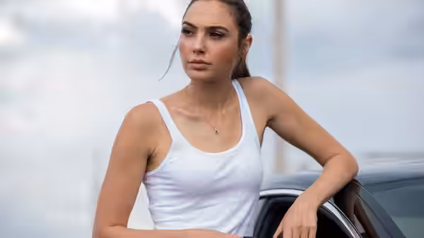 Gisele Yashar (Gal Gadot) leans against a car on the beach