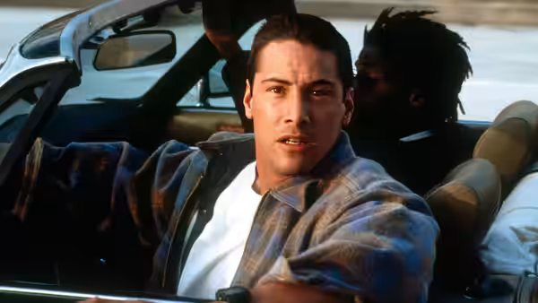 Jack Traven (Keanu Reeves) driving a convertible with a passenger