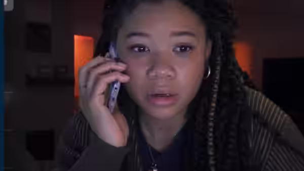 June (Storm Reid) holding a phone to her ear with mouth open