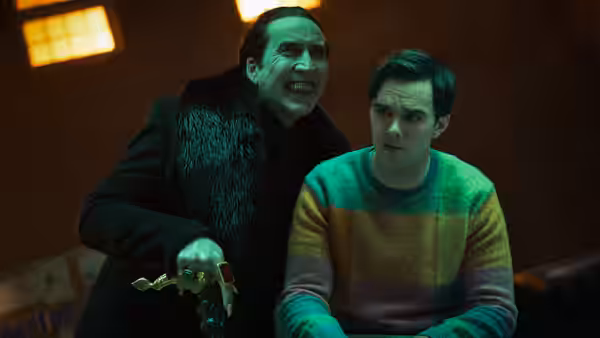 Dracula (Nicolas Cage) stands over seated Renfield (Nicholas Hoult) holding a chalice
