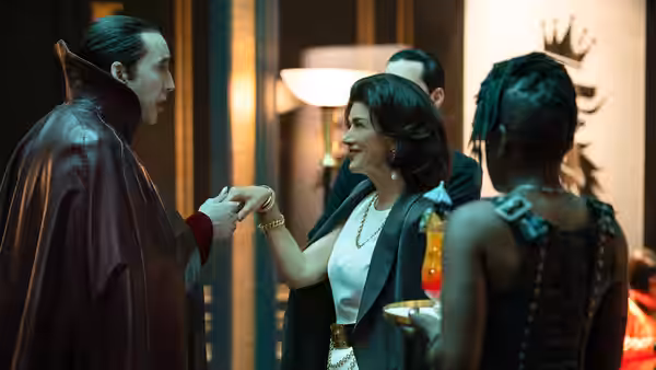 Renfield (Nicholas Hoult) shakes hands with a woman at a party