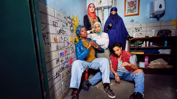 Group of women in a graffiti-covered bathroom with one seated on a chair
