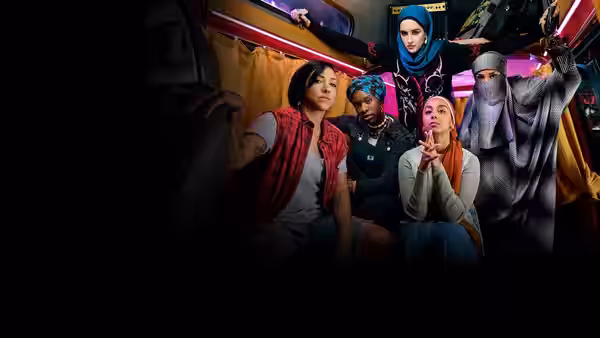 Five women in headscarves posing together inside a neon-lit vehicle