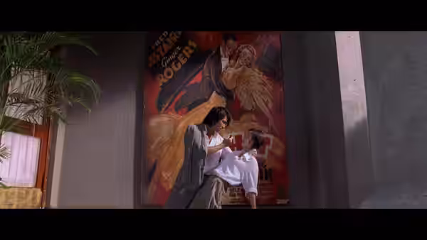 Sing (Stephen Chow) supports a woman in white beneath a martial arts film poster