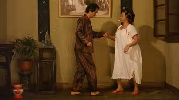 Sing (Stephen Chow) reaches toward Landlady (Yuen Qiu) in a warmly lit room