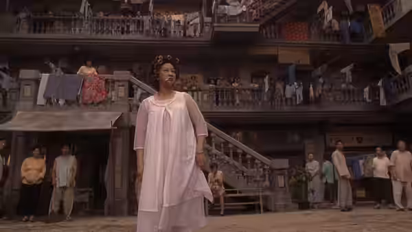 Landlady (Yuen Qiu) stands in her nightdress in the crowded Pig Sty Alley courtyard