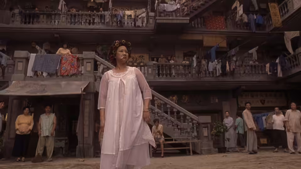 Landlady (Yuen Qiu) stands in her nightdress in the crowded Pig Sty Alley courtyard