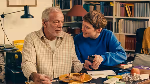 Georg (Pascal Greggory) and Sandra (Léa Seydoux) sit at a desk with food