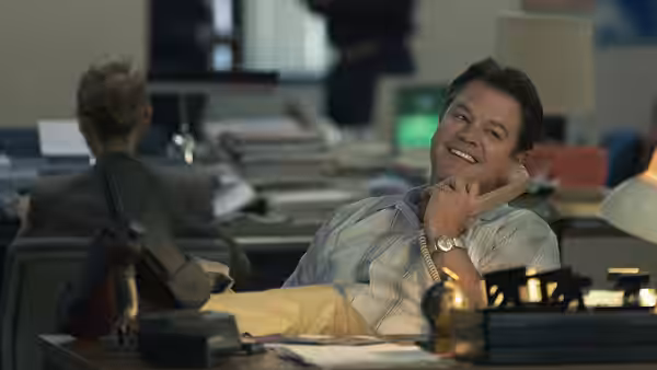 Rob Strasser (Jason Bateman) smiling on phone at office desk