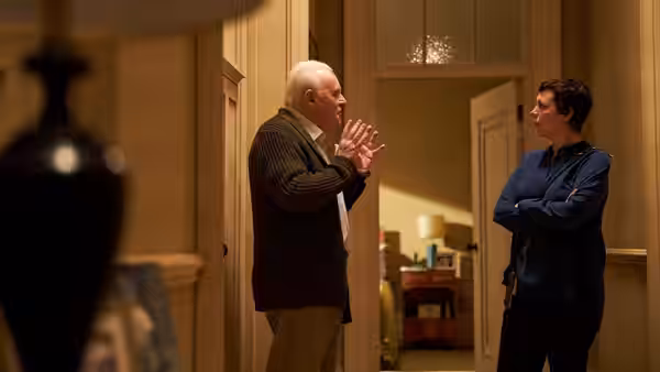 Anthony (Anthony Hopkins) gestures while speaking to Anne (Olivia Colman) in a hallway
