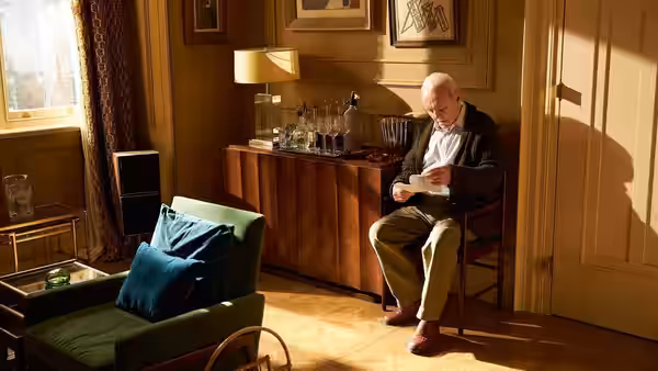 Anthony (Anthony Hopkins) sits reading a newspaper in a sunlit room by a window