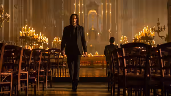 John Wick (Keanu Reeves) walking down the aisle of a candlelit church