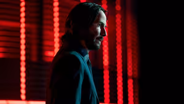John Wick (Keanu Reeves) standing in profile against red neon lights