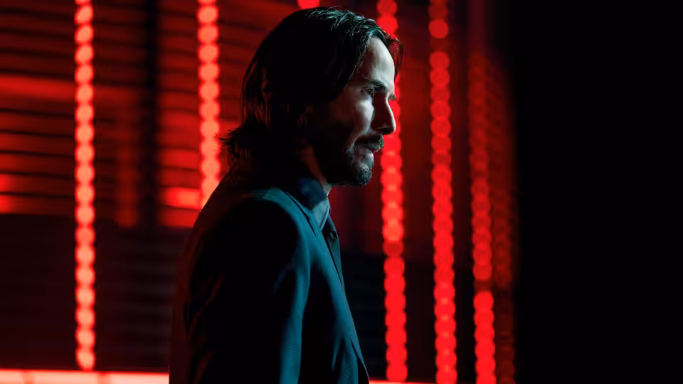 John Wick (Keanu Reeves) standing in profile against red neon lights