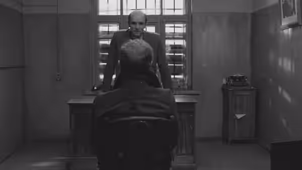 Portnov (Anatoly Solonitsyn) interrogates a seated prisoner across a desk