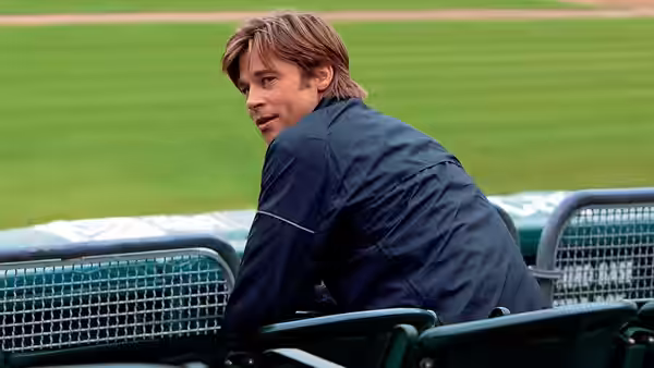 Billy Beane (Brad Pitt) sits in the dugout looking back over his shoulder