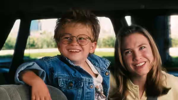 Ray Boyd (Jonathan Lipnicki) and Dorothy Boyd (Renée Zellweger) smiling in a car