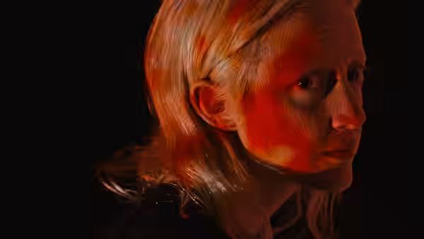 A blonde woman turns toward the light in a dark room