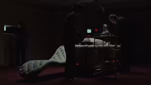 Several people gather around a person lying on a table in a dark laboratory