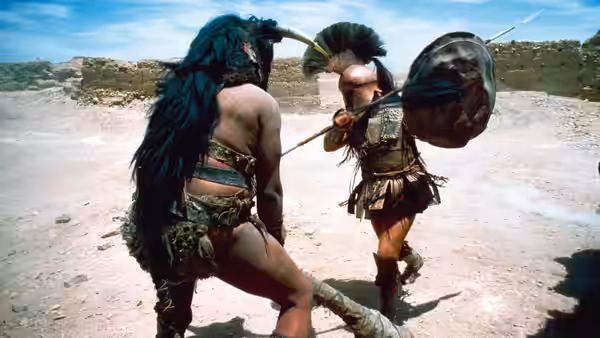 Two armored warriors clash with swords and shields on a dusty plain